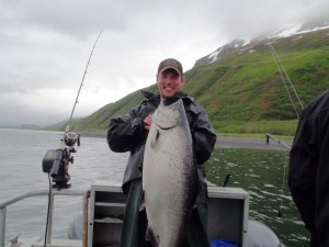 A man on a fishing boat holding a large king salmon at Kodiak Sportsman's Lodge In Kodiak Island