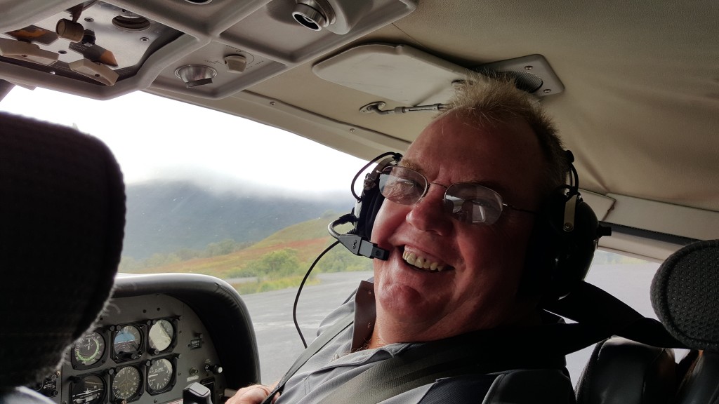 Man in front seat of plane with headset on smiling